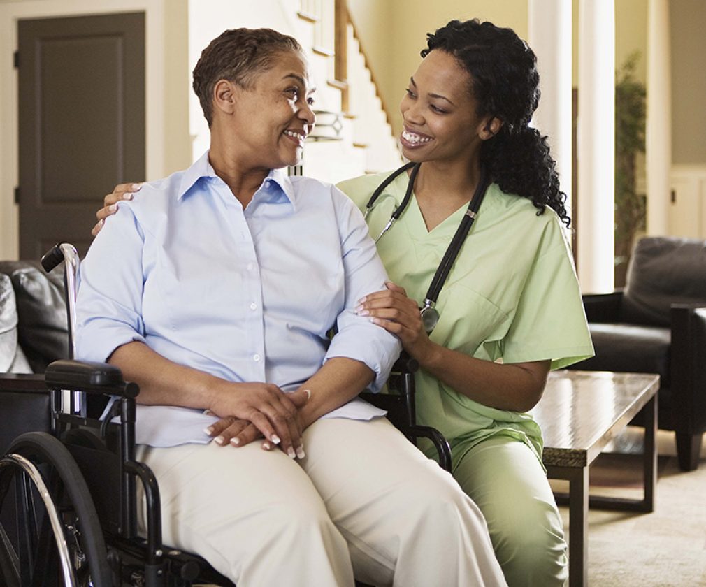 Nurse with woman in wheelchair at home